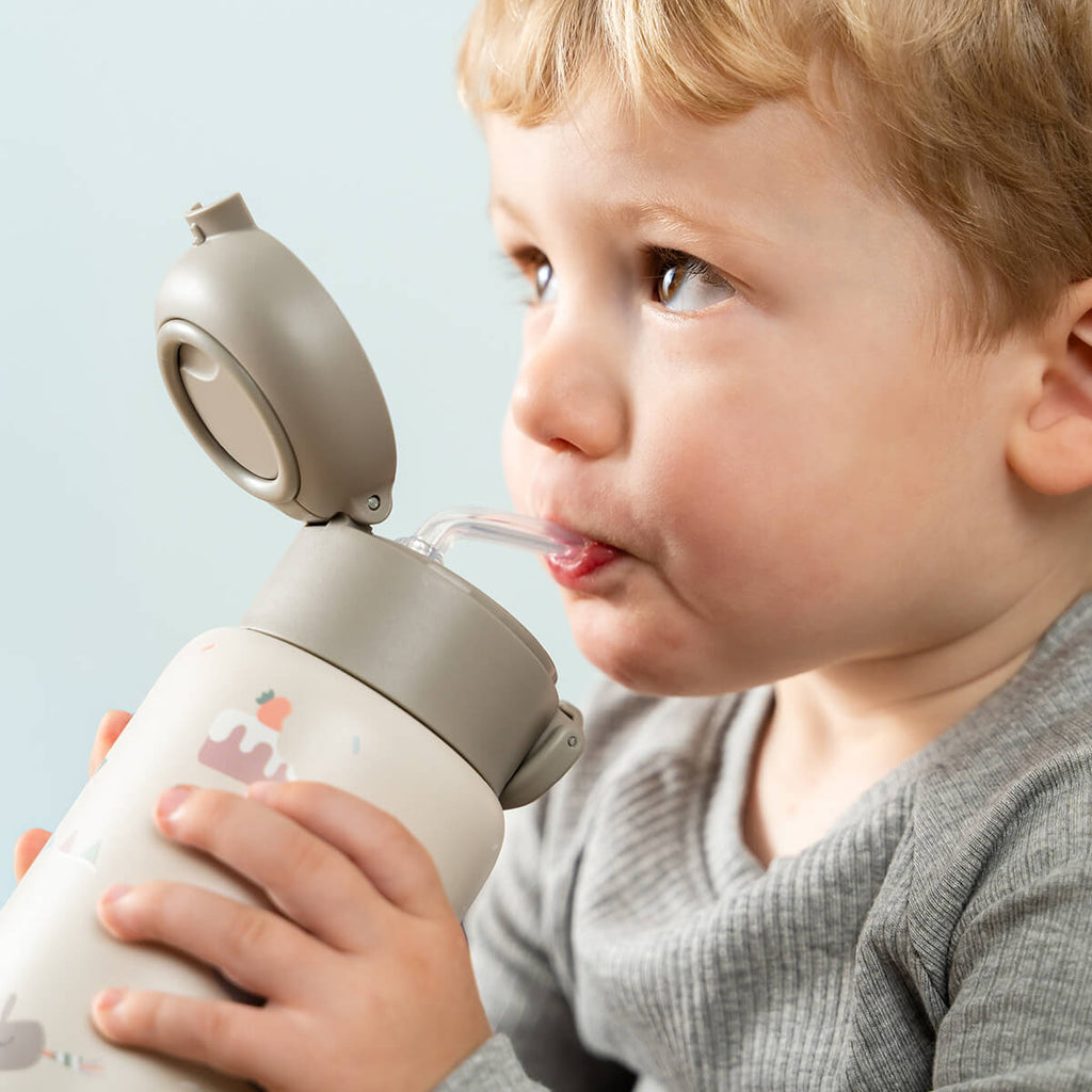 Kindje drinkt uit de Done By Deer thermosfles Celebration Sand