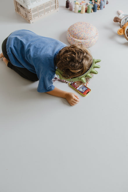 Kidywolf Kidyears Dino, jongen kruipt op de grond met de koptelefoon op