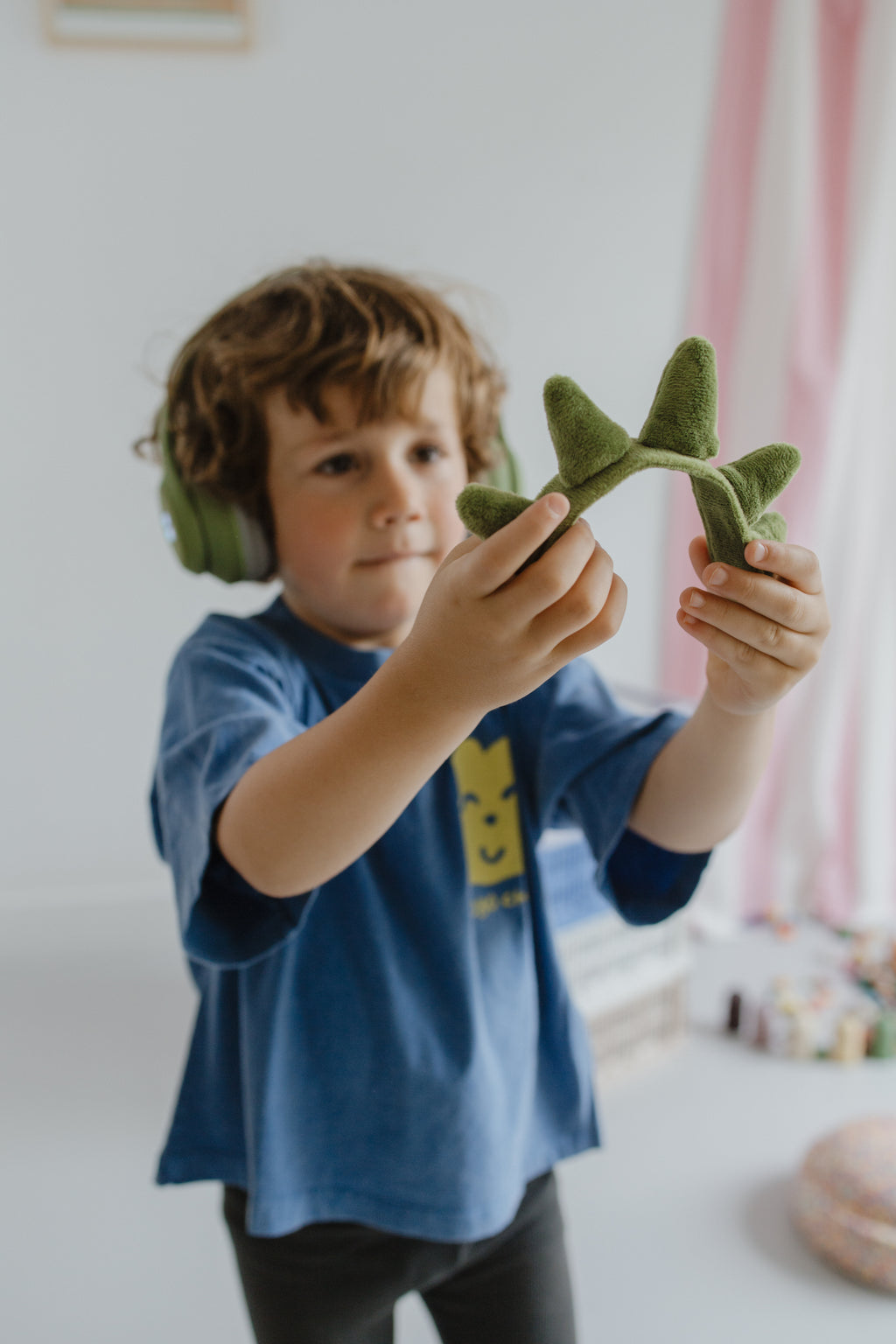 Kidywolf Kidyears Dino, jongen speelt met een speelgoeddino en de koptelefoon op
