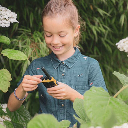 Kidywolf Kidytalk walkie talkie, meisje bekijkt het toestel tussen de planten