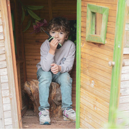 Kidywolf Kidytalk walkie talkie, jongen zit met het toestel in de deur van een speelhuisje