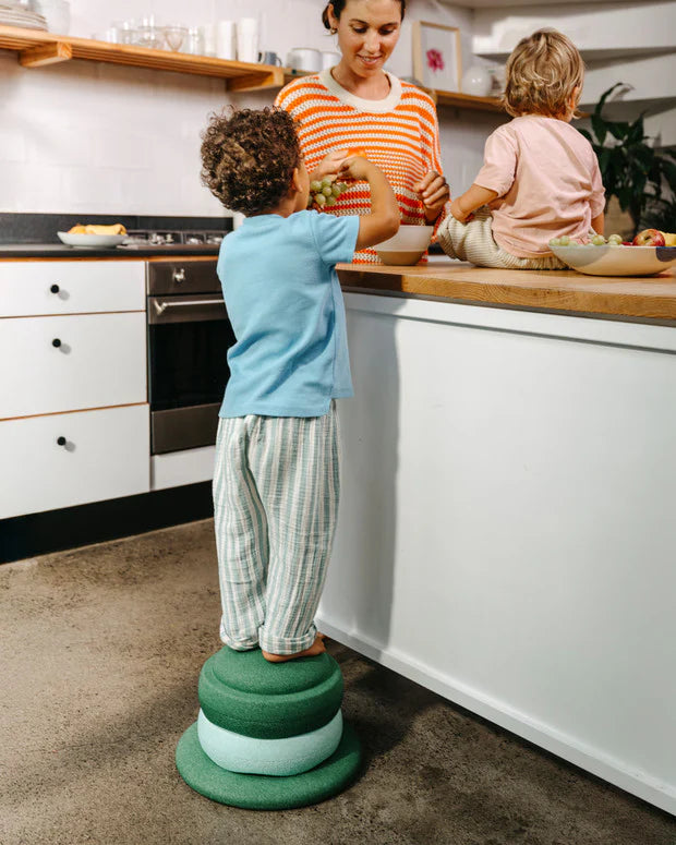 Stapelstein Balance Board Dark Green, kind staat op een opstapje van stenen in de keuken
