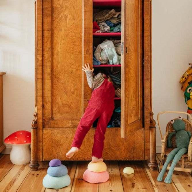 Stapelstein Inside Pastel Rainbow, kind speelt bij een open kast met stenen op de vloer