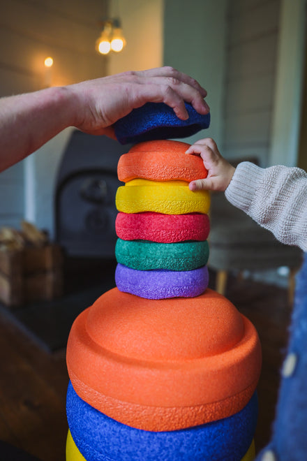 Stapelstein Original Mini Rainbow Classic, hand stapelt mini stenen op een grote oranje steen