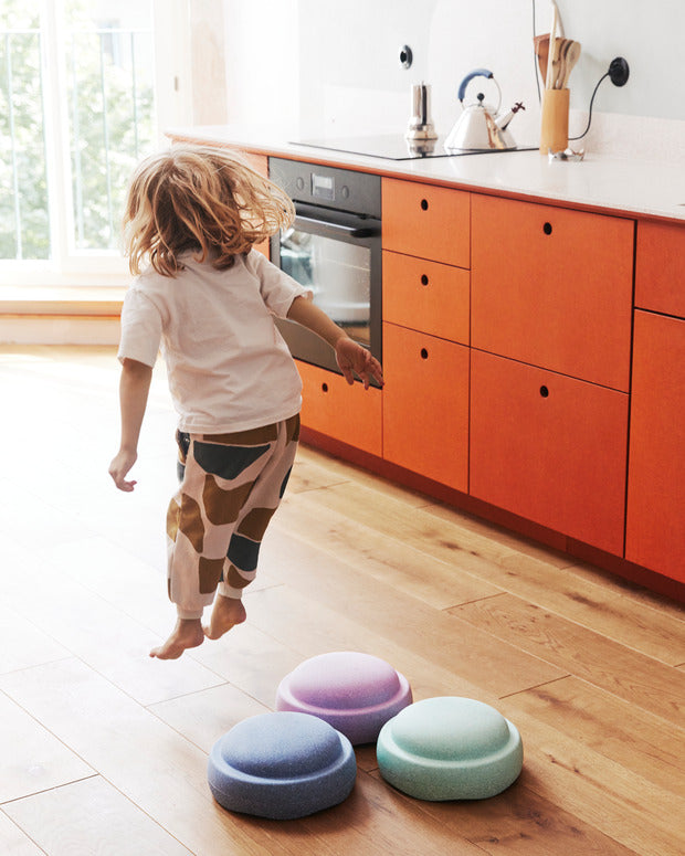 Stapelstein Original Rainbow Cool Pastel, kind springt over de stenen in de keuken