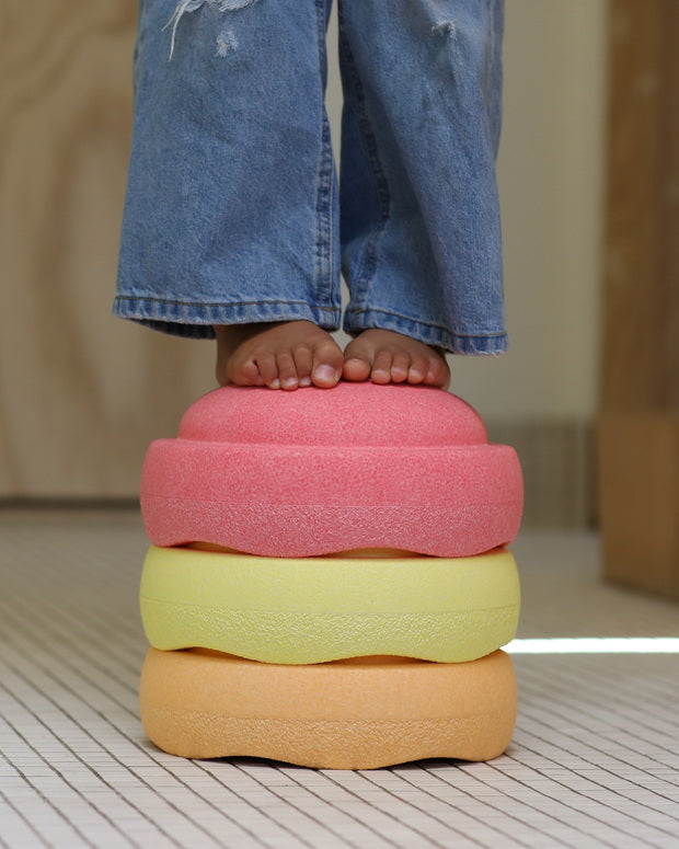 Stapelstein Original Rainbow Warm Pastel, close-up van kindervoeten op gestapelde stenen