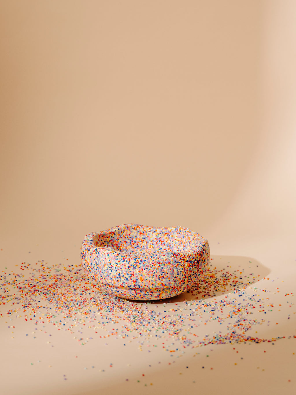 Stapelstein Steen Super Confetti, omgekeerd als schaaltje op een zandkleurige achtergrond