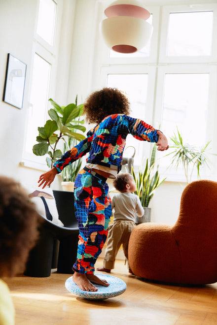 Stapelstein Balance Board Super Cool, kind balanceert staand op het bord in de woonkamer