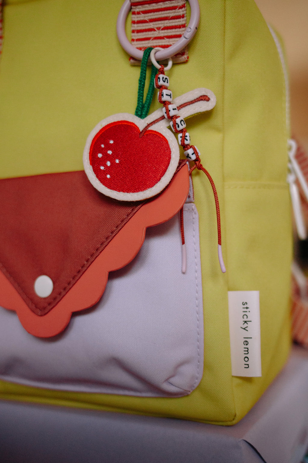 Sticky Lemon Rugzak Small Sticky Memories Special Edition Cherry On The Cake, close-up van het voorvak en de sleutelhanger