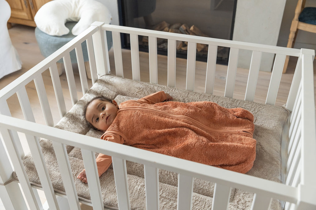 Timboo 4-seizoenen slaapzak bamboe babymaat Sunrise Orange, baby slaapt in de slaapzak in een houten bedje