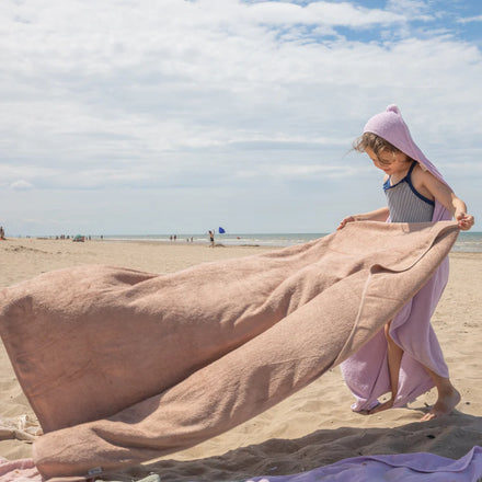 Timboo extra grote handdoek bamboe Feather Grey, sfeerbeeld vrouw met een roze handdoek op het strand