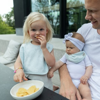 Timboo bamboe slab met drukknoop Riviera Blue, gedragen door een peuter in de zetel