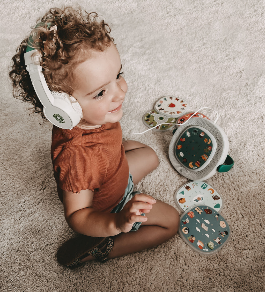 Timio hoofdtelefoon, peuter met koptelefoon speelt op de grond met de speler en discs