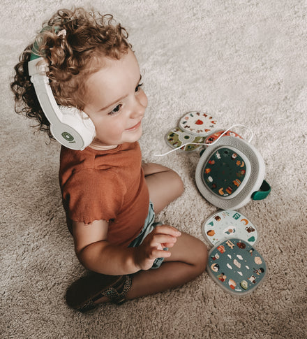 Timio hoofdtelefoon, peuter met koptelefoon speelt op de grond met de speler en discs