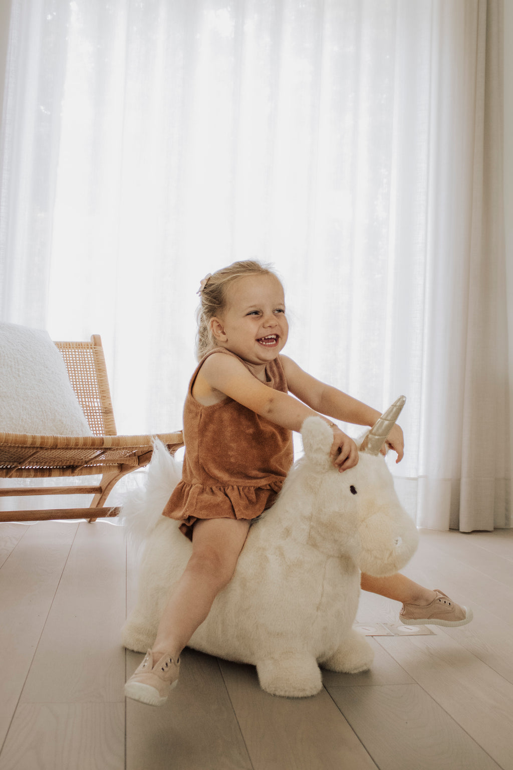 Wild & Soft Bouncy Eenhoorn, meisje wipt op de eenhoorn met gespreide armen