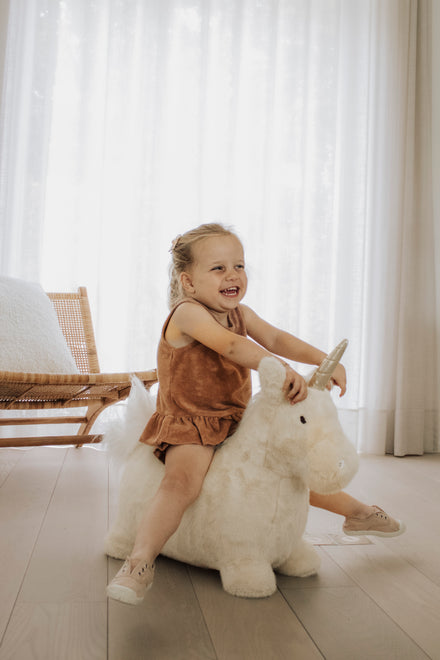 Wild & Soft Bouncy Eenhoorn, meisje wipt op de eenhoorn met gespreide armen