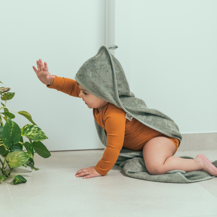 Timboo badcape bamboe Savannah Sand, sfeerbeeld baby kruipt met een badcape over de rug