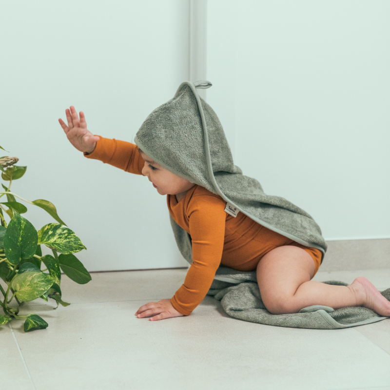 Timboo badcape bamboe Savannah Sand, sfeerbeeld baby kruipt met een badcape over de rug